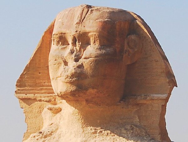 Tourists standing in front of the Great Pyramids and the Sphinx.