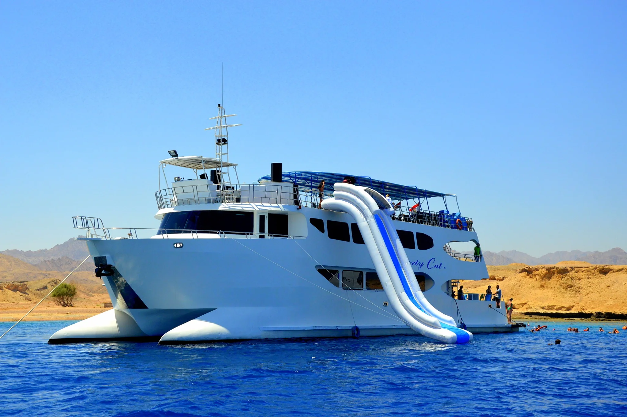 A family on a glass-bottomed catamaran smiling at colorful fish and coral reefs.  